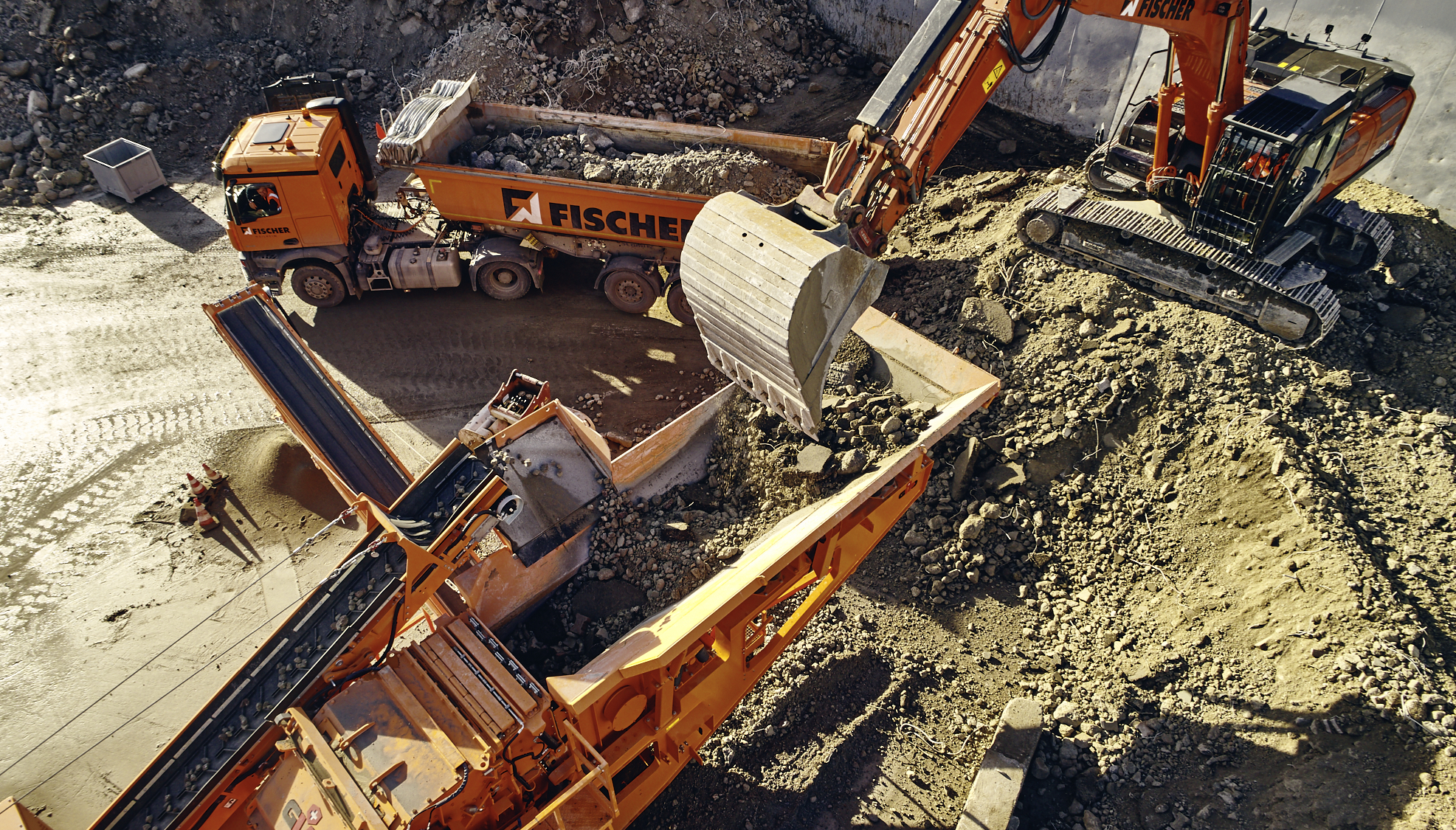 Kettenbagger befüllt vollelektrischen Brecher mit mineralischem, recyclingfähigem Material.