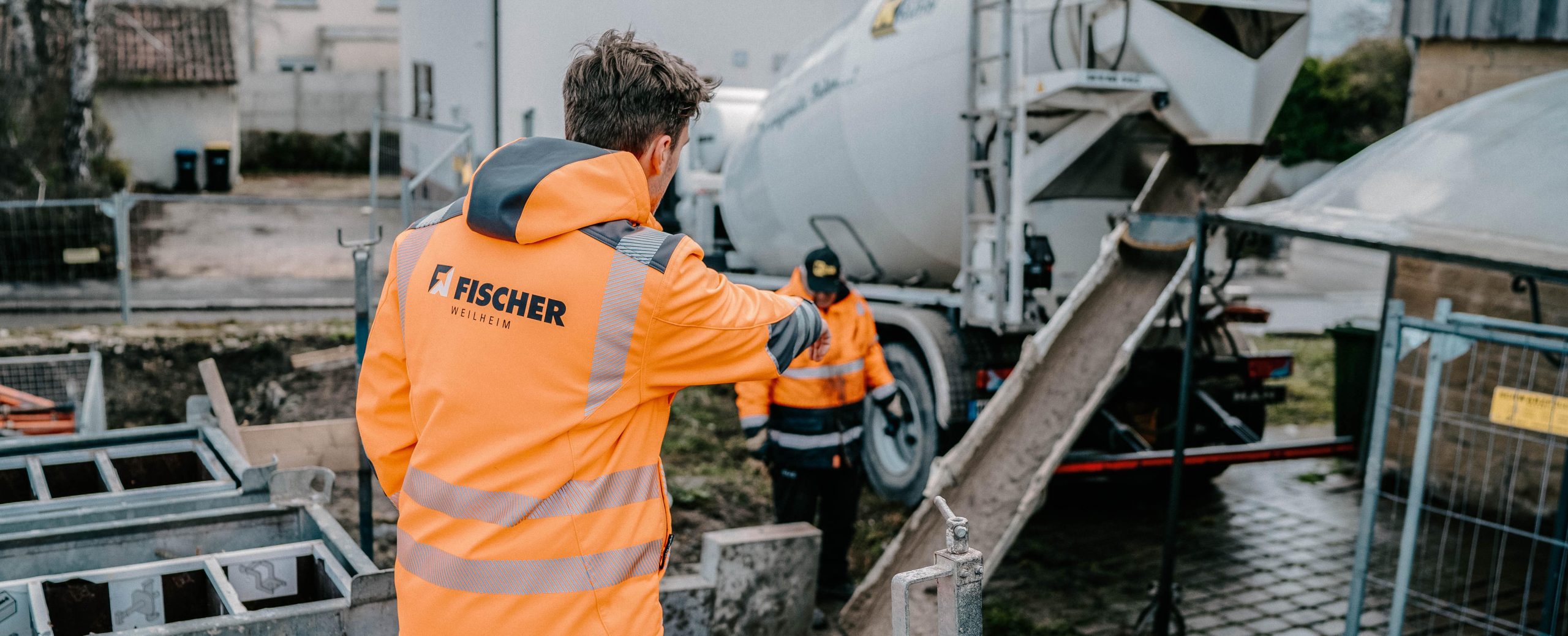 Bauleiter von FISCHER, der vor einem Fahrmischer steht und beobachtet, wie Flüssigboden verfüllt wird