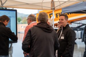 Gäste vor einem digitalen Bildschirm im Außenzelt beim FISCHER Lunch 2026